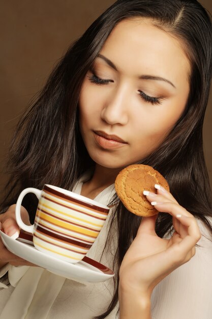 Photo asian woman with coffee and cookies.