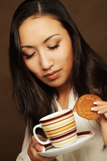 Asian woman with coffee and cookies.