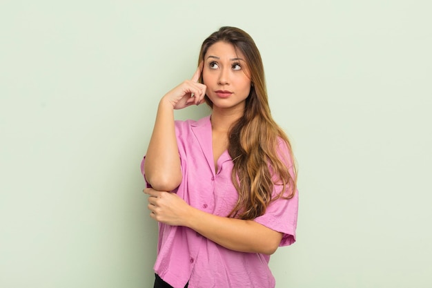 asian woman with a concentrated look, wondering with a doubtful expression, looking up and to the side