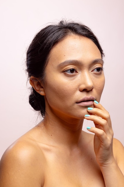 Asian woman with dark hair wearing blue nail varnish touching mouth