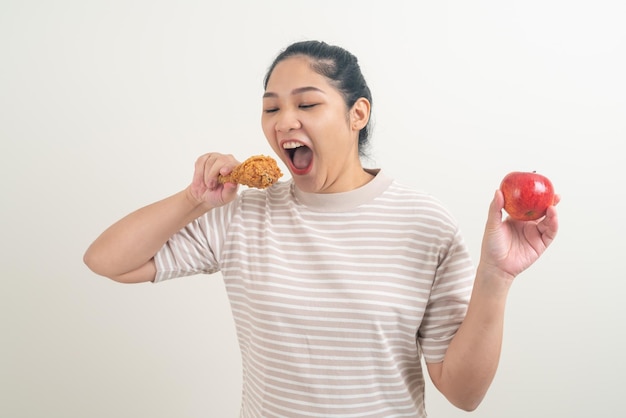 手にフライド チキンとリンゴを持つアジアの女性