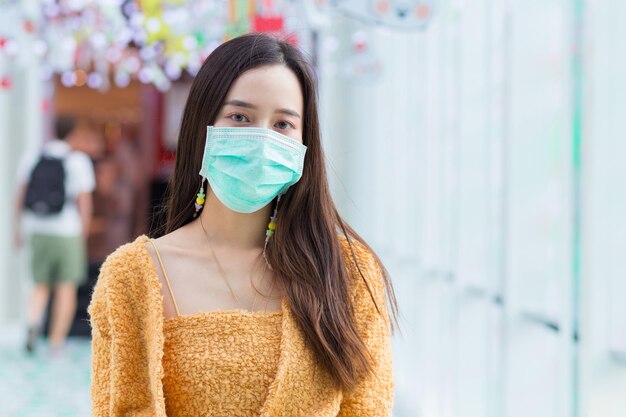 Asian woman with long hair wears knitwear and medical face mask in health care new normal concept