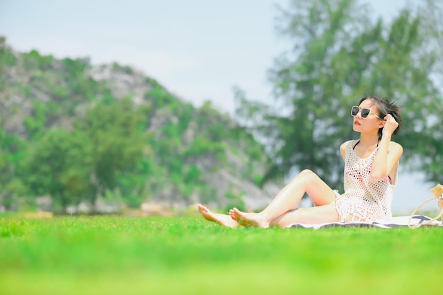 夏の公園で毛布の上に座ってピクニック バスケットを持つアジアの女性