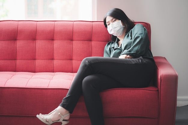 Asian woman with protective face mask sleeping on sofa feeling tired and sick