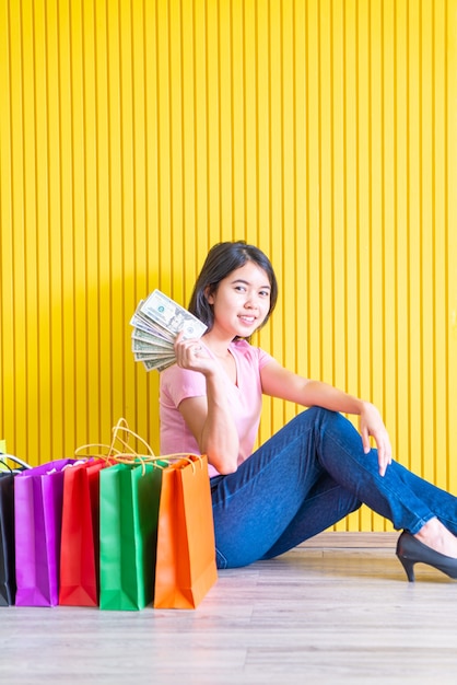 Asian woman with shopping bags holding notes