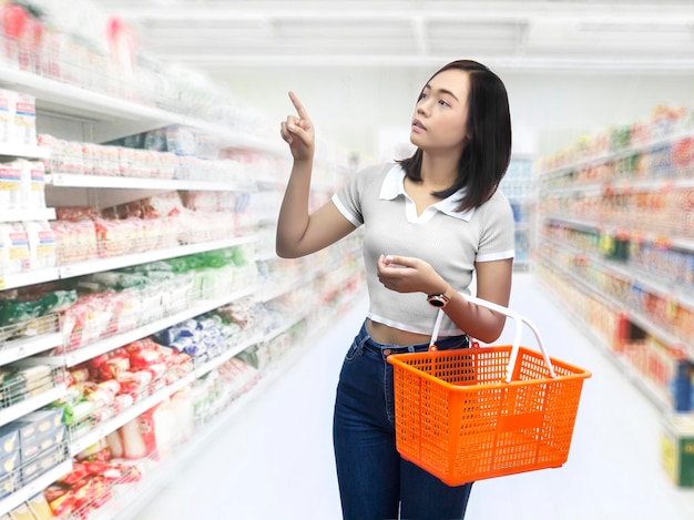 Asian woman with shopping basket on department store to choose goods in business concept