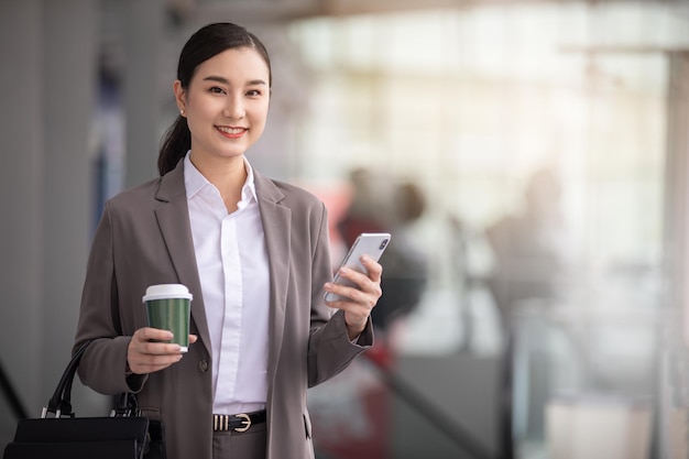 Asian woman with smartphone standing against street blurred building background