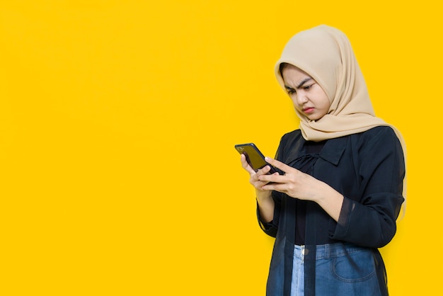 Asian woman with smartphone on yellow wall