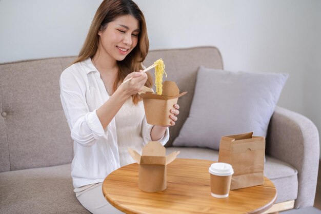 Asian woman with takeaway food and drinks at home consumption eating home delivery food enjoying delicious takeaway delivery tasty meal