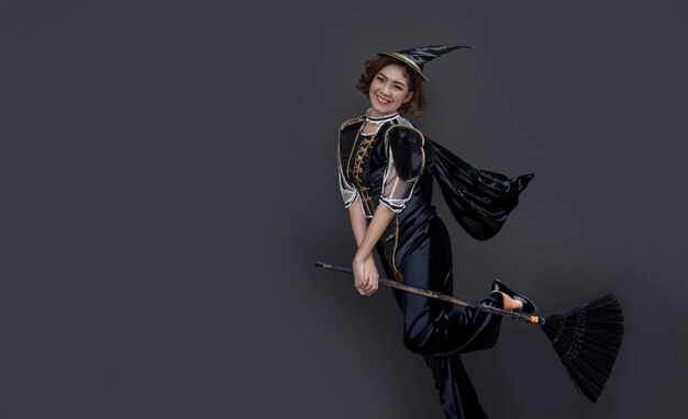 Фото Азиатская женщина в костюме ведьмы и старой метле для хэллоуинской вечеринки концепция на изолированном фоне для рекламы в фестивале хэллоуэна