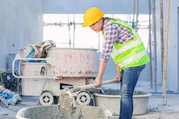Азиатская женщина-работница, трудолюбивая в качестве рабочего персонала на строительной площадке, смешивает бетонный цемент вручную