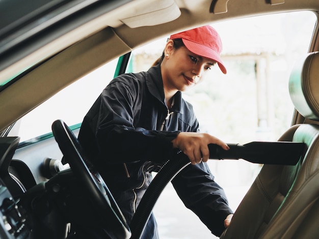 Asian woman worker washing car at garage