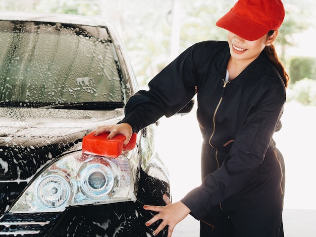 Asian woman worker washing car at garage