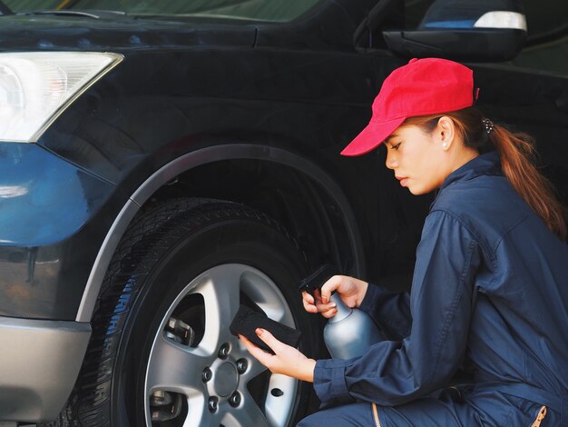 Asian woman worker washing car at garage