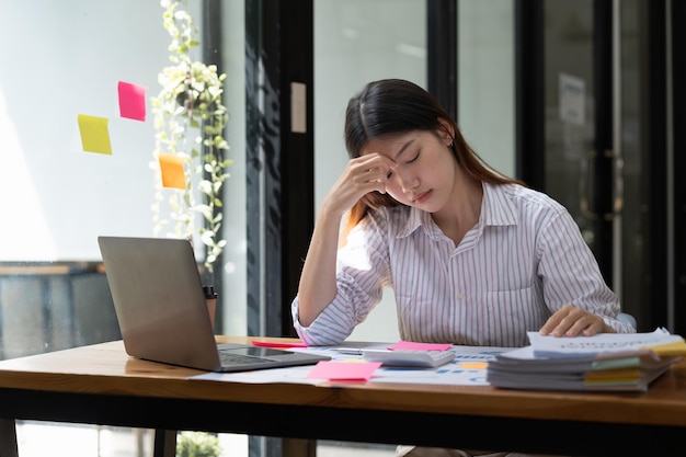 アジアの女性は深刻なストレスと頭痛で一生懸命働いていますが、オフィスの女性は一生懸命働くコンセプトで仕事に問題を抱えています