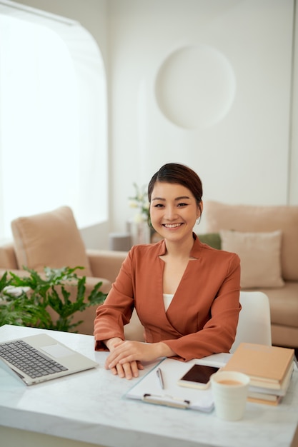 Asian woman working in home office with laptop.