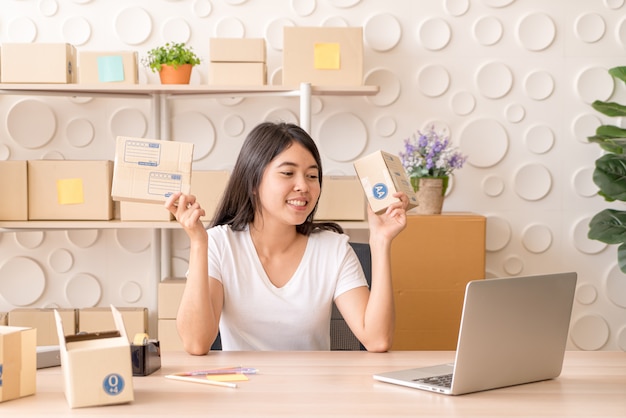 Asian woman working at home with packing boxes