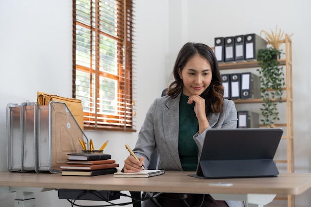 사무실에서 노트북 컴퓨터에 대한 비즈니스 재무 분석을 위해 노트북을 사용하는 아시아 여성