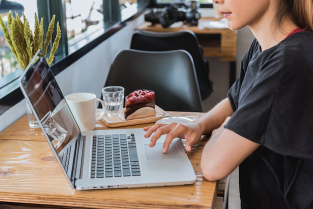 Asian woman working on laptop computer in cafe.