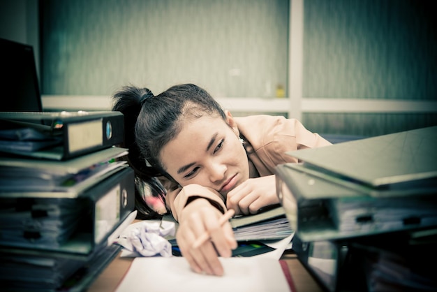 Азиатская женщина, работающая в офисе, молодая деловая женщина испытывает стресс от перегрузки работой с большим количеством файлов на столе