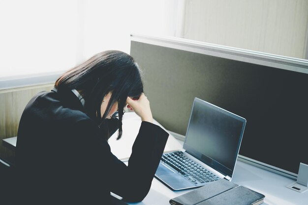 オフィスで働くアジアの女性若いビジネスウーマンは机の上にたくさんのファイルで仕事の過負荷からストレスを感じているタイの人々は何かを考えています