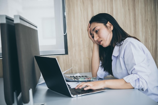 オフィスで働くアジアの女性若いビジネスウーマンは、deskthailandの人々にたくさんのファイルで仕事の過負荷からストレスを感じました