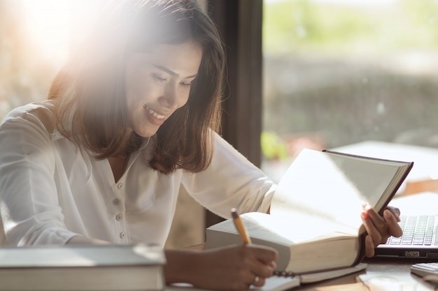 アジアの女性が働いて、幸せで本を読んでいます。