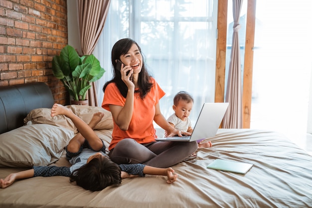 Asian woman working while taking care of children