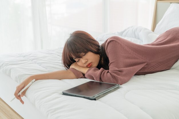 Asian woman working with tablet on bed