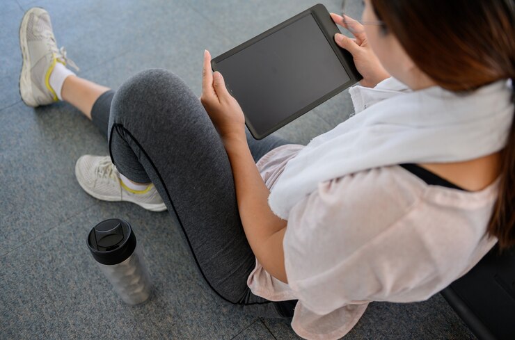 アジアの女性のトレーニングとGYMで一人でオンラインで働いています。社会的距離と新しい通常のライフスタイル。