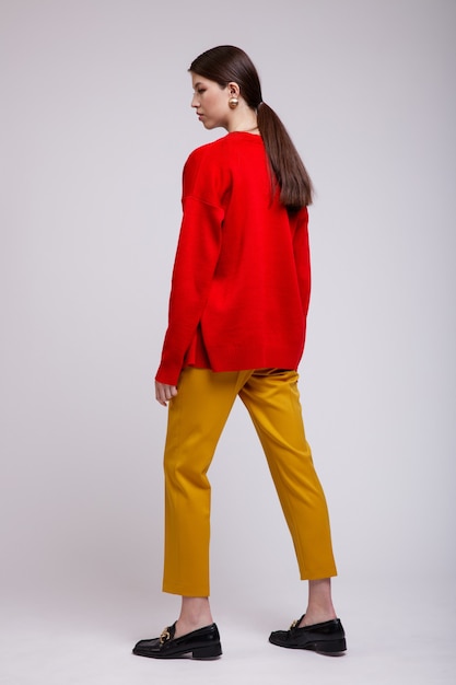 Asian woman in yellow pants red cardigan green tshirt belt on white background Studio Shot