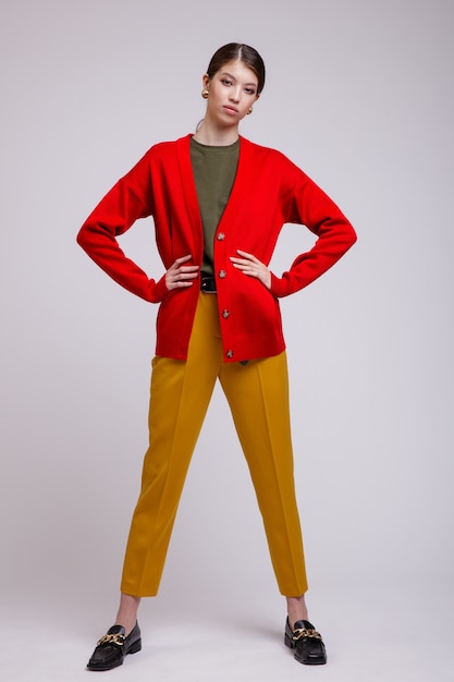 Asian woman in yellow pants red cardigan green tshirt belt on white background Studio Shot