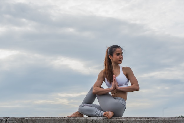 Asian woman in yoga pose on top of wall.