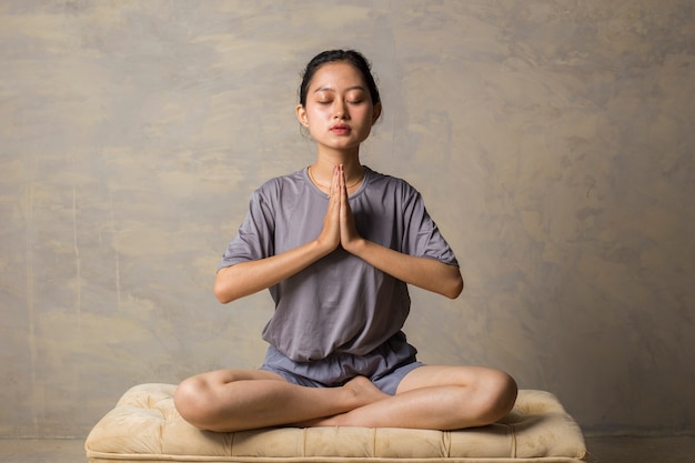 Asian woman do yoga practice meditating indoors lotus position