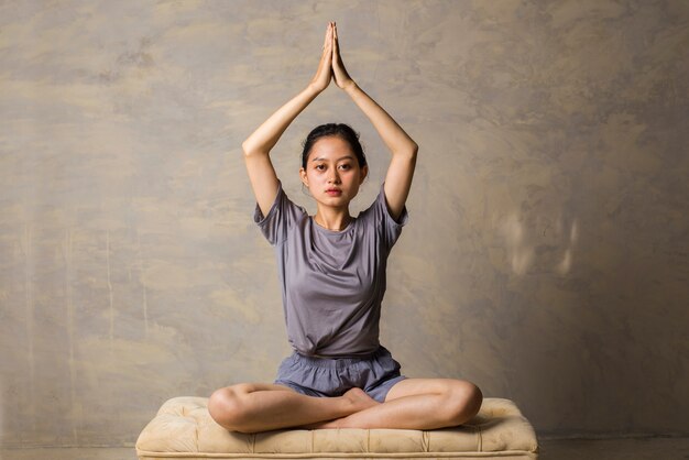 Foto la donna asiatica fa la pratica di yoga che medita la posizione del loto all'interno