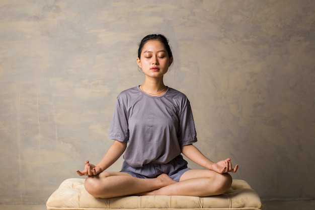 Asian woman do yoga practice meditating indoors lotus position