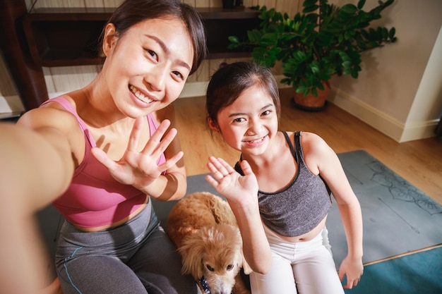 Asian woman yoga teacher and little girl filming yoga online class on video