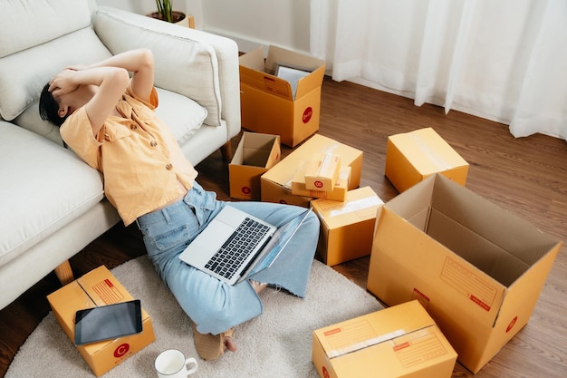 Asian womans business owner is stressing and un comfortable surrounded by boxes