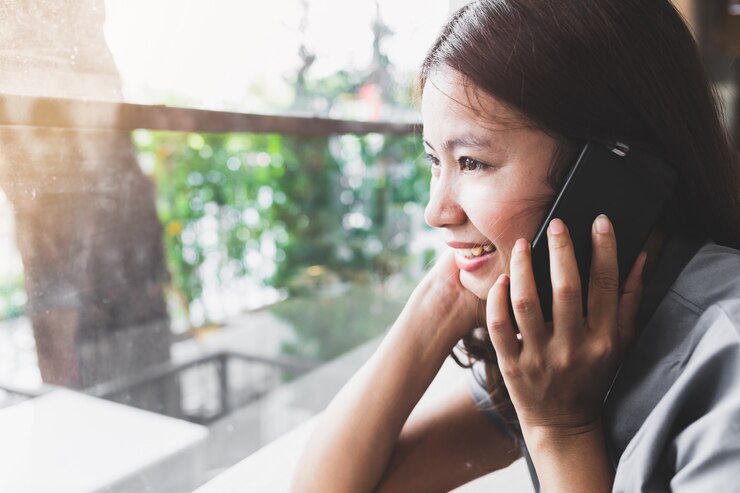 Photo アジアの女性はコーヒーショップで携帯電話に話すのがうれしいです