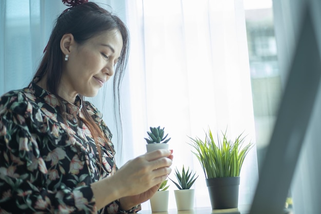 アジアの女性はラップトップでオンライン販売のための植物を提示しています