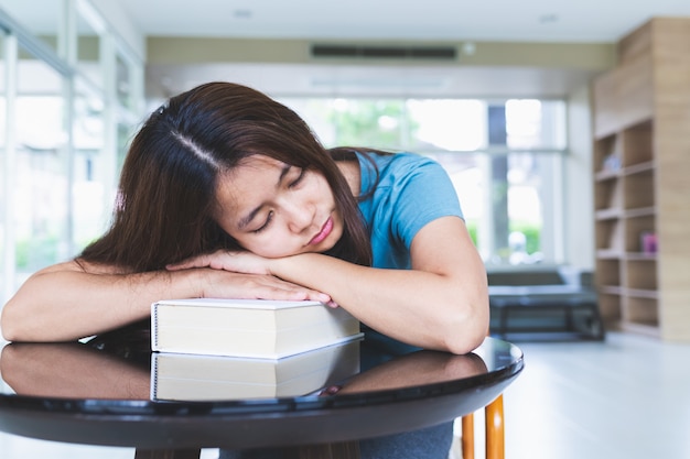 アジアの女性は図書館で本を読んだ後寝ています