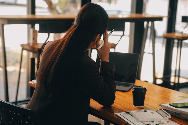 Photo asian women are stressed while working on laptop tired asian businesswoman with headache at office feeling sick at work copy space