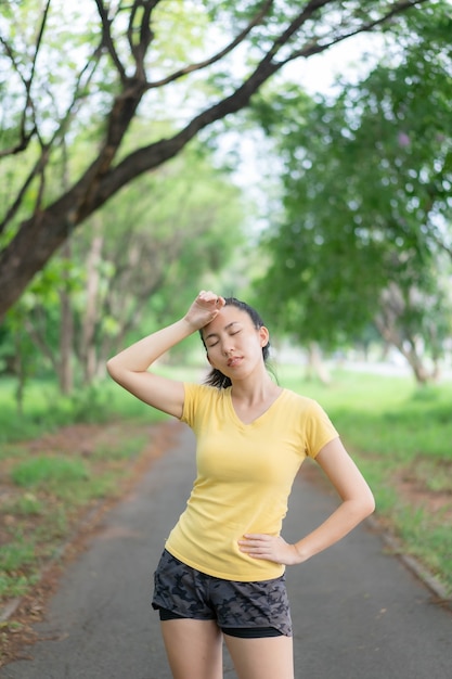 アジアの女性は公園で運動する前にストレッチしています。