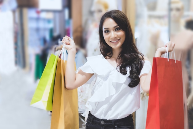 アジアの女性と美しい女の子が買い物をしているショッピングバッグを持っています