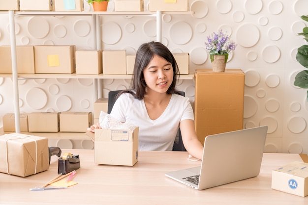asian women business owner working at home with packing box on workplace