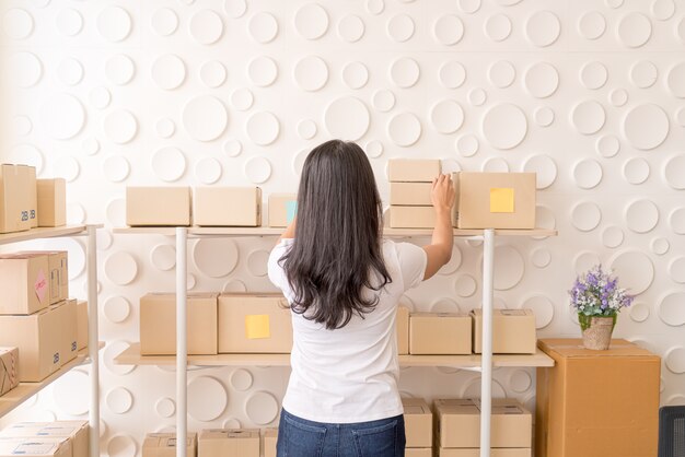 Asian Women business owner working at home with packing box on workplace