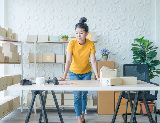 Imprenditore asiatico delle donne che lavora a casa con il contenitore di imballaggio sul posto di lavoro