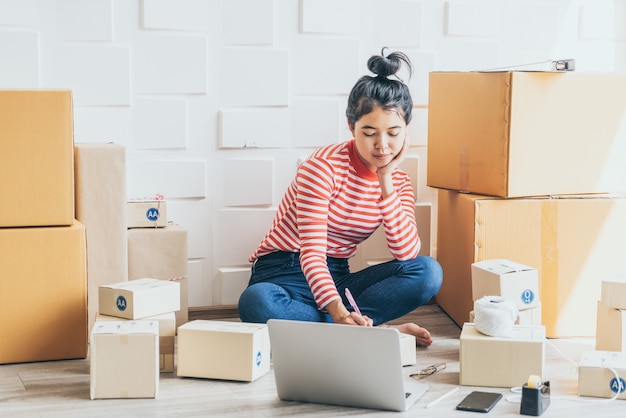 Asian Women business owner working at home with packing box on workplace