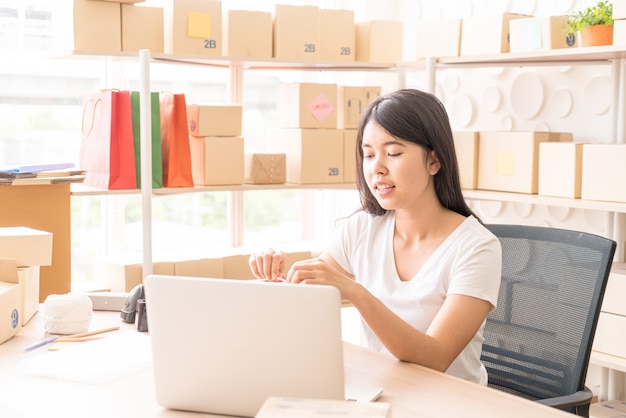 Asian Women business owner working at home with packing box on workplace