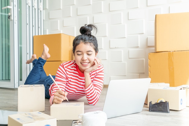 Imprenditore asiatico delle donne che lavora a casa con il contenitore di imballaggio sul posto di lavoro